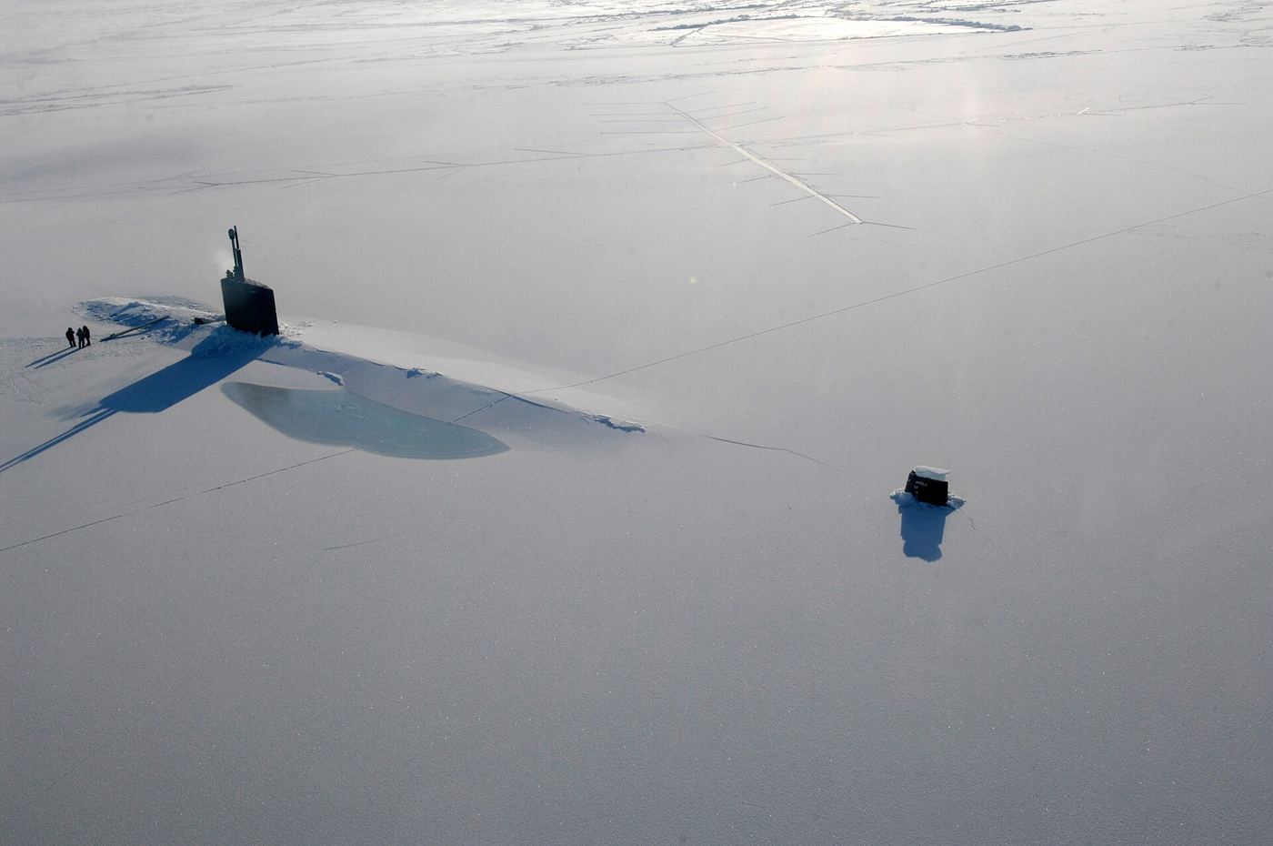 Aerial view of fractured arctic sea ice floating on dark ocean water with melt pools.